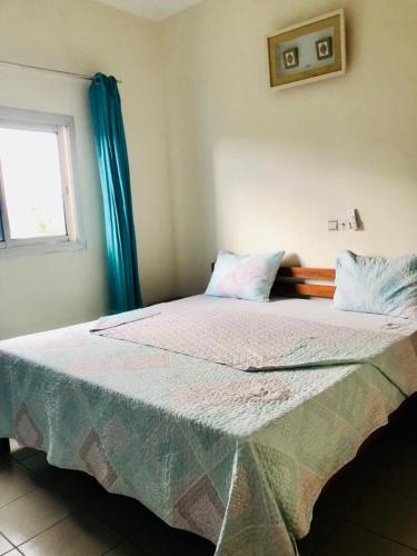 duże łóżko w pokoju z oknem w obiekcie GMJ Résidence w mieście Duala