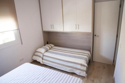 Habitación pequeña con 2 camas y armarios blancos. en Mont-Roig Apartment, en Cambrils