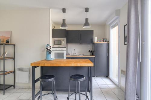 a kitchen with a counter and two bar stools at Le Souclin - Ma Cabotte in Lagnieu