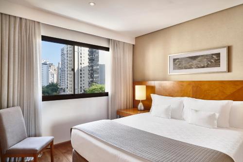 um quarto de hotel com uma cama e uma janela em George V Casa Branca em São Paulo
