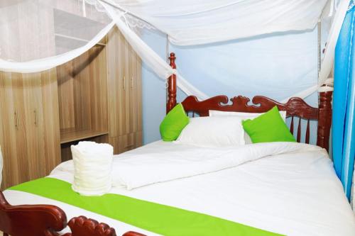 ein Schlafzimmer mit einem Himmelbett mit grünen und weißen Kissen in der Unterkunft Gerly Homes in Kakamega