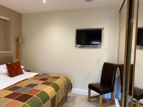 a hotel room with a bed and a tv on the wall at The Byre @ Cow Close - Stay, Rest and Play in the Dales. in Leyburn