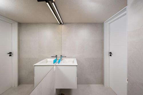 a white bathroom with a sink and a mirror at Krasiński Garden Apartments in Warsaw