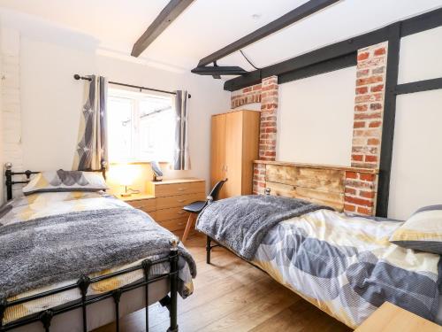 a bedroom with a bed and a brick wall at Squirrel Lodge in North Walsham