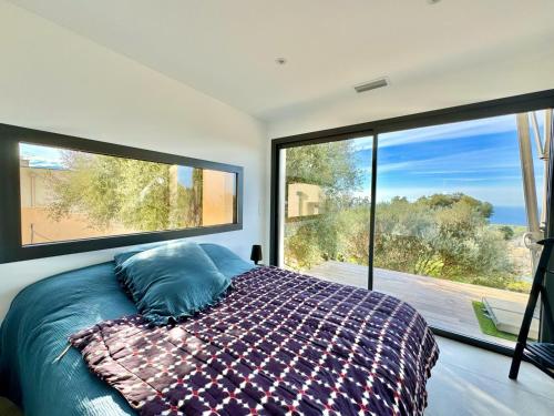 une chambre avec un lit devant une grande fenêtre dans l'établissement Super villa moderne corbara vue mer, à Corbara
