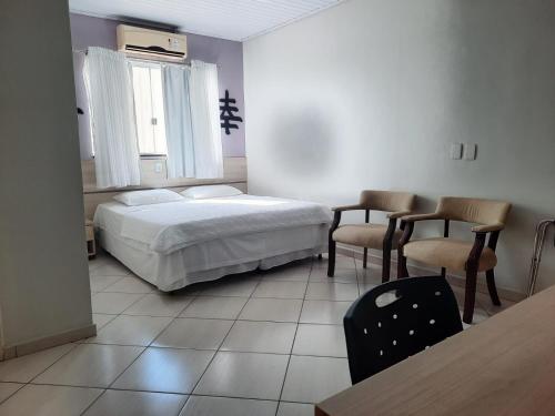 Laras Hotel Ltda في Acailandia: غرفة نوم بسرير وكرسيين وطاولة