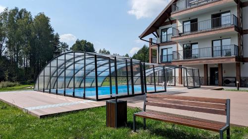 a glass bridge over a swimming pool next to a building at Apartamenty Sun & Snow Zapach Lasu - Naturalne SPA in Karwica