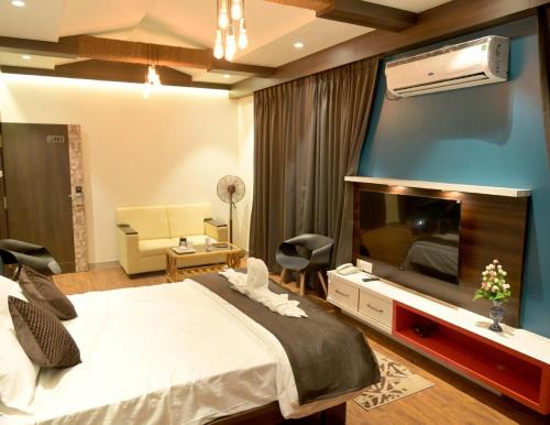 a bedroom with a large bed and a flat screen tv at Hotel Limelight in Kudal
