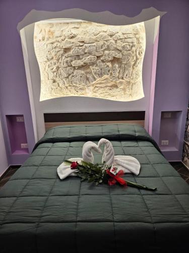 a bed with two towels and flowers on it at LUXUITE Spa con Piscina o Jacuzzi in Alberobello