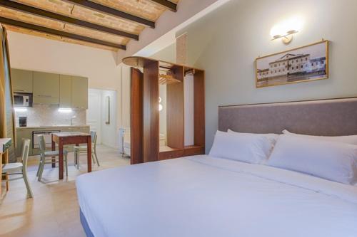 a bedroom with a white bed and a kitchen at Villino Mari in Ascoli Piceno