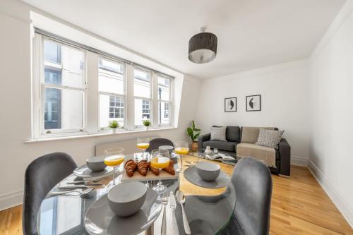 a dining room with a glass table and chairs at Holborn & Central London with Balcony - CityApartmentStay in London