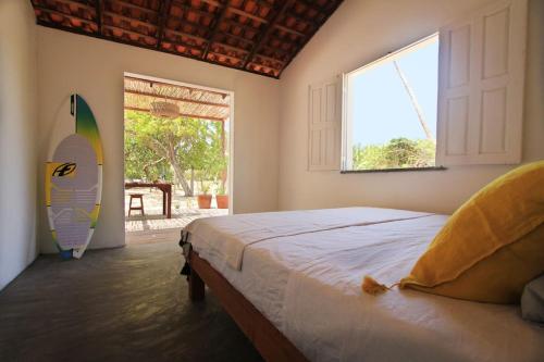 um quarto com uma cama e uma prancha de surf ao lado de uma janela em Villa Shanti em Atins