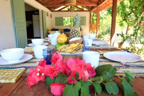 uma mesa com pratos, tigelas e flores em Villa Shanti em Atins
