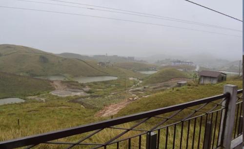 a view of a hill with a fence and water at GREEN HILLS in Cherrapunji