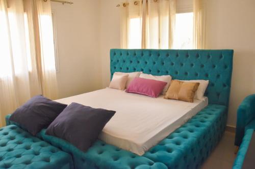 a bedroom with a blue bed with pillows on it at Le petit coccon de LUZ in Mbour