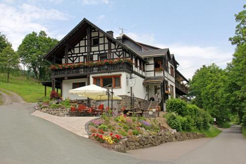 a house with an umbrella and flowers in front of it at Landidyll Landhaus Liesetal in Hallenberg