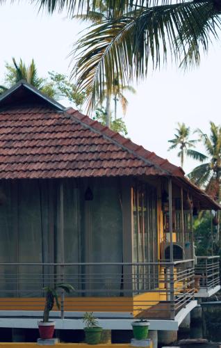 a house with a porch and a palm tree at Vrindavan homestay in Munroe Island