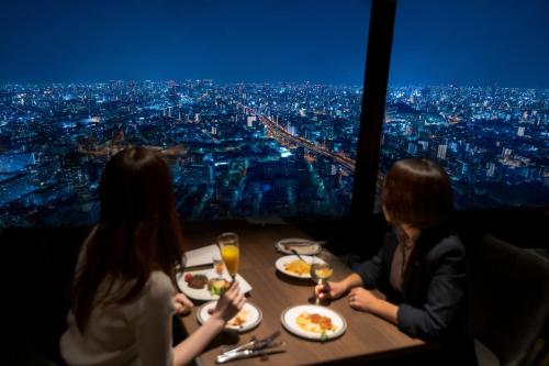 un grupo de personas sentadas en una mesa con platos de comida en Art Hotel Osaka Bay Tower, en Osaka