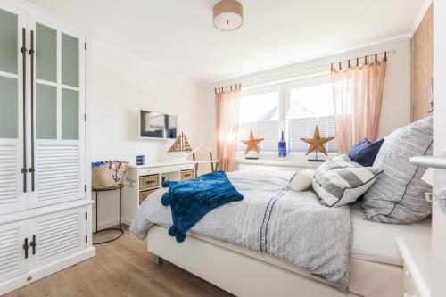 a white bedroom with a bed and a desk at Strandlust in Zingst