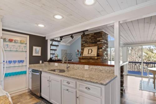 a kitchen with a sink and a fireplace at Stay On The Cape Vacation Rentals: Contemporary Saltbox In New Seabury in Mashpee