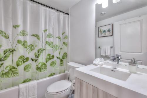 e bagno con servizi igienici e tenda da doccia con piante. di RivetStays - The Jarvis a Toronto