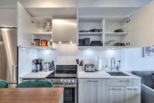 a kitchen with white cabinets and a stove top oven at RivetStays - The Jarvis in Toronto