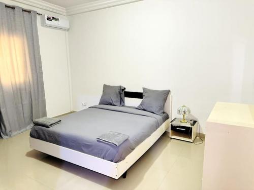 um quarto branco com uma cama grande e almofadas azuis em Maison fonctionnelle idéalement située à Dakar em Dakar