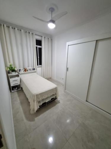 Dormitorio blanco con cama y espejo grande en Quarto confortavel privativo Copacabana, en Río de Janeiro