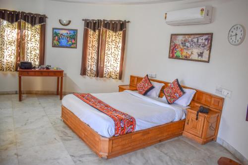 a bedroom with a bed and a table and windows at RESORT FARM VILLA in Bhuj