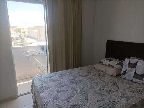 a bedroom with a bed and a large window at Apartamentos Beira Mar in Laranjal