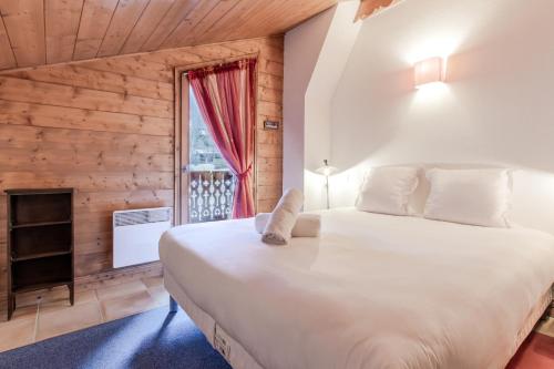 une chambre avec un grand lit blanc et une fenêtre dans l'établissement Les Grandes Jorasses - Calme - Duplex, aux Houches