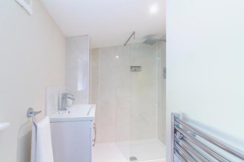 a white bathroom with a shower and a sink at Cairngorms Cottage in Cray