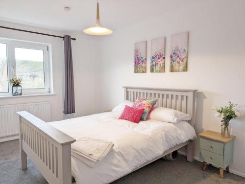 a bedroom with a bed with white sheets and pink pillows at Family Home in Rustington, West Sussex in Rustington