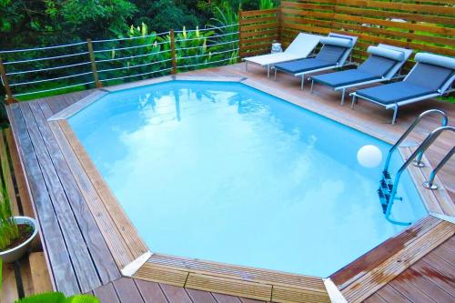 een groot zwembad op een houten terras met stoelen bij Appartement de 2 chambres avec terrasse et wifi a Gros Morne in Gros-Morne