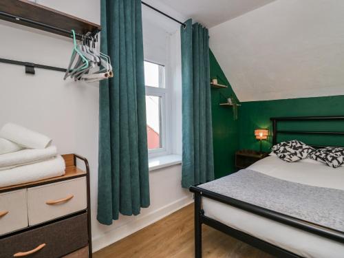 a bedroom with green curtains and a bed and a window at 5C Queen Street in Whitehaven