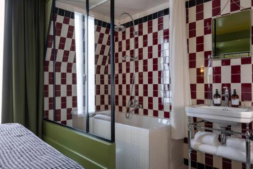 a bathroom with a tub and a sink and a shower at Hôtel La Conversation in Paris