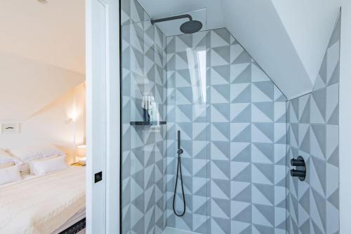 a bathroom with a shower with a blue tiled wall at The Modern Cottage in Whitstable