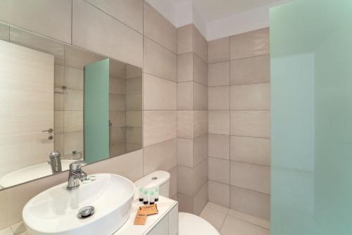 a bathroom with a sink and a toilet and a mirror at Beach Break Rhodes in Faliraki
