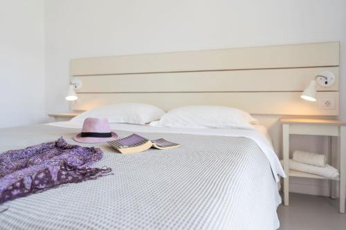 a bed with a hat and two books on it at Beach Break Rhodes in Faliraki