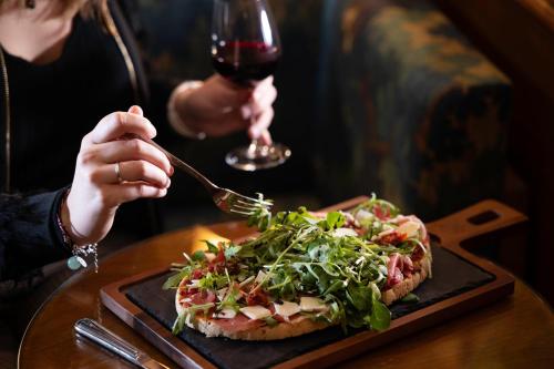 a woman eating a pizza with a glass of wine at Hôtel La Conversation in Paris