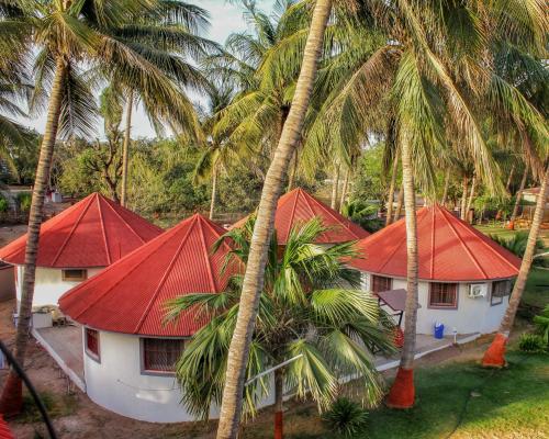 a group of houses with red roofs and palm trees at RESORT FARM VILLA in Bhuj