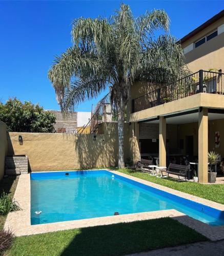 a swimming pool in front of a house with a palm tree at Los Martínez Apart in Paganini
