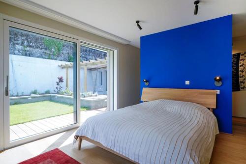 ein Schlafzimmer mit einem blauen Kopfteil und einem großen Fenster in der Unterkunft Contemporary Penthouse with Cinema room and breath-taking Lakeview in Lausanne