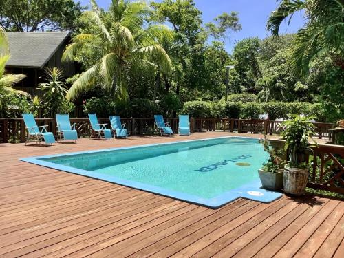 a swimming pool on a wooden deck with blue chairs at Patti's Paradise in Sandy Bay