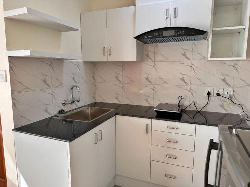 a kitchen with white cabinets and a sink at Shakya House in Pātan