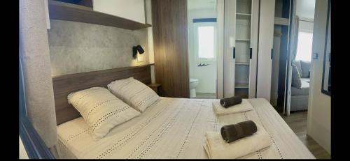 une chambre avec un lit avec des draps blancs et des oreillers dans l'établissement Mobilhome neuf La Dolce Vita, à Claouey