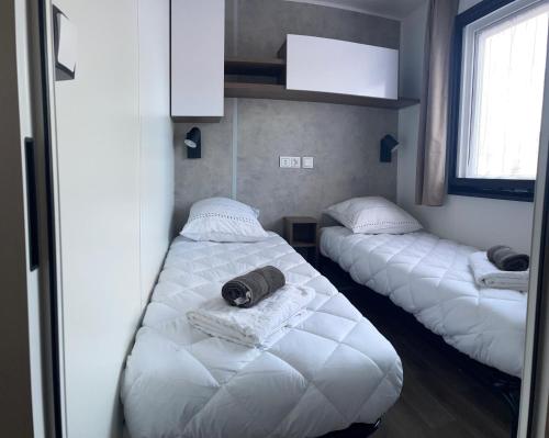 two beds in a room with white blankets at Mobilhome neuf La Dolce Vita in Claouey