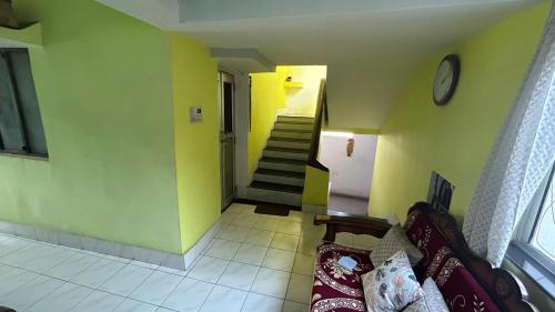 um quarto com paredes amarelas e uma escada com um sofá em Debnath Homes em Jamshedpur