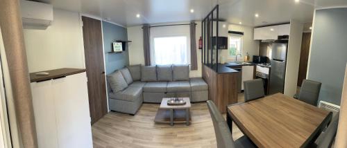 a small living room with a table and a kitchen at Mobilhome neuf La Dolce Vita in Claouey