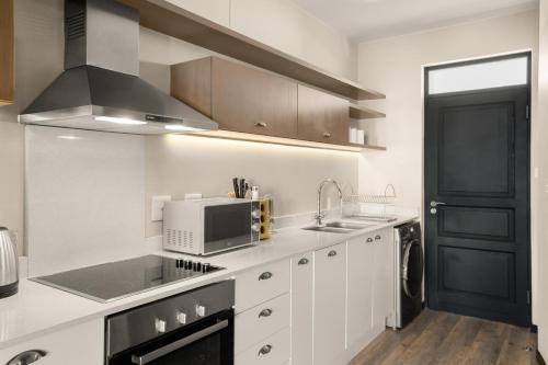 a white kitchen with a sink and a microwave at Easy Stay - The Vantage Rosebank in Johannesburg